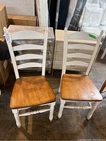 Front view of two wooden ladder back dining chairs with white frames and natural wood seats placed side by side.