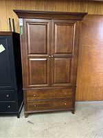 Front view of wooden media cabinet with closed double doors and two drawers below