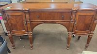 Front view of the Pulaski buffet cabinet showing carved wood legs and door details.