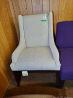 Front view of the beige Stanley Furniture armchair showing its wingback design and fabric upholstery with wood legs.