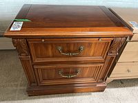 Front view of Stanley Furniture wood bedside table showing two drawers with metal pull handles and carved decorative details on the corners.