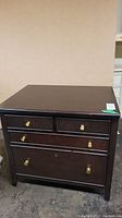 Front view of Stanley solid wood file cabinet showing dark finish and brass knobs on all drawers.