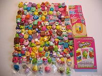 Overview of all Shopkins figures laid out, including unopened sealed bags, collector cards, and jumbo playing cards deck.