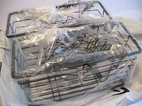 Two black metal wire bathroom organizer baskets wrapped in clear plastic packaging.