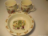 Three-piece Royal Doulton Bunnykins set, comprising one porringer bowl and two matching cups, showing exterior designs.