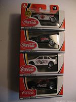 All 4 unopened Matchbox Coca-Cola branded cars stacked vertically in original packaging.