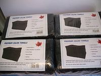 Four packages of compressed black towels, each labeled as Premium Salon Towels by JA, 12 towels per package, totaling 48 towels.