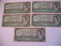 Five 1967 Canadian Centennial one dollar bills laid out in two rows. Each bill features Queen Elizabeth II, the centennial maple leaf emblem, serial numbers, and Bank of Canada text. The bills show varying wear and usage.