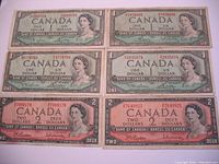 Photo showing six used 1954 Canadian banknotes: four $1 bills in green and two $2 bills in pink with Queen Elizabeth II portraits and serial numbers visible.