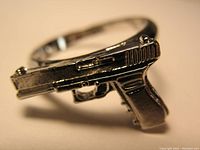 Close-up side view of a silver-toned pistol-shaped ring.