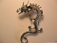 Close-up front view of the silver-tone gothic dragon ear wrap showing detailed facial and body features.