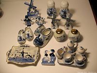 Full collection on table including tall and small salt and pepper shakers, miniature clogs, figurines of Dutch children, tray, tea set, and round salt and pepper shakers with gold tops.