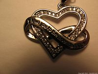 Close-up image of the heart-shaped pendant showing clear rhinestones and inscription.