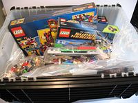 Container with LEGO sets boxed and loose parts visible inside plastic bags.