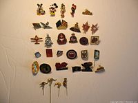 Full lot arranged on a flat surface showing Disney, military, tourist, 1986 Expo, Snowbirds pins and four Australian stick pins