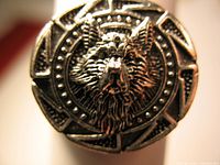 Close-up of the ring face showing the detailed wolf head design surrounded by Viking-style geometric and dot patterns.