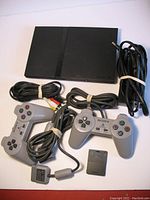 Sony PlayStation 2 SCPH-70011 console, two wired controllers, AV cable, power adapter, and 8MB memory card displayed together