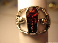 Front view of the skeletons carrying red coffin ring showing red coffin centerpiece with cross insignia and skeleton figure details