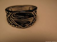 Close-up image of the metal Superman ring highlighting the raised stylized 'S' shield emblem with ornate sides.