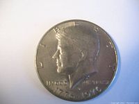 Obverse side of Kennedy half dollar showing profile of John F. Kennedy with dates 1776-1976.