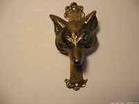 Top view of brass wolf door knocker showing full length with decorative mounting points and detailed wolf face.