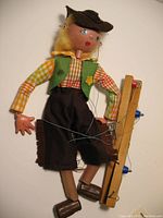 Vintage Pelham Cowgirl Marionette-style wooden puppet with green vest, checkered shirt, and brown pants seated with string control bar.