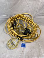 Full view of 20ft yellow extension cord string lights with five bulbs covered in yellow metal guards for protection.