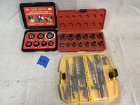 Full view of the three sets: Super Socket set in small black and red case, Craftsman hex socket set in larger red case, and yellow plastic case with assorted bits