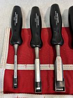 Four Craftsman chisels arranged side by side on a red fabric tool roll, showing front view of handles and blades with size markings.