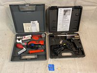 Overview of the lot showing two open plastic cases containing soldering irons and accessories side by side on a neutral surface.