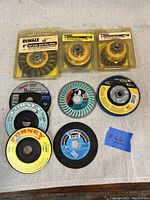 Top down photo of assorted grinder and wire brush wheels on a beige surface, showing product labels and packaging