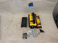 Overall view of the yellow and black GRRR-Ripper System by Micro Jig laid on a fabric backdrop with slip pad, T-handle, and bag of hardware nearby.