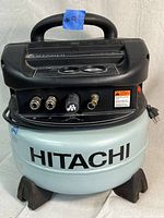 Front view of Hitachi EC510 pancake compressor showing tank, connectors and regulator knob.