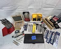 Overview of the large lot showing multiple sets of drill bits in cases, loose bits, and specialty bits