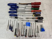 Top view showing full assortment of 29 screwdrivers arranged in rows on fabric surface.