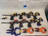 Top view of 12 mini bar clamps arranged on cloth showing various brands and colors including Irwin, Craftsman, and Quick-Grip.