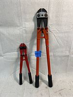 Pair of bolt cutters, one large Craftsman with orange handles and one smaller red Jet cutter.