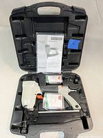 Open carrying case displaying the Porter Cable FN250B finish nailer, instruction manual, and packs of nails inside molded compartments.