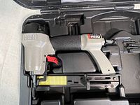 Side view of Porter Cable NS100A stapler loaded with narrow crown staples, inside molded plastic carrying case.