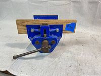 Front view of the blue Record woodworking vise with wooden jaw attached, showing the handle and quick release lever.