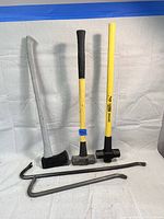 Front view showing two sledgehammers, one axe, and two pry bars laid out on white background.