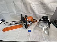 Overview of chainsaw, bar scabbard, and safety helmet with ear muffs and face shield
