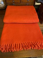 Folded thick dark tangerine wool blanket showing full folded shape and color.