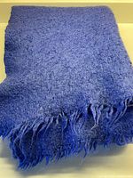 Royal blue mohair felted blanket folded with fringed edge displayed.