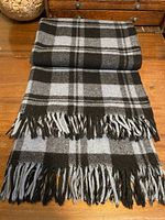 Folded grey and black checked wool blanket showing fringed edge detail