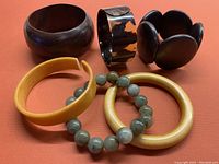 Overview of six bracelets on orange background