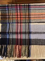 Full view of the scarf laid flat showing the multi-coloured check pattern and fringed ends.