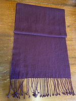 Scarf folded to show full length and fringed ends on wooden surface.