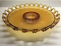 Front angle view showing amber glass platter with loop cutout scalloped rim and attached footed base.