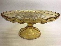 Full side view of the amber glass footed cake plate showing scalloped edges and pedestal base